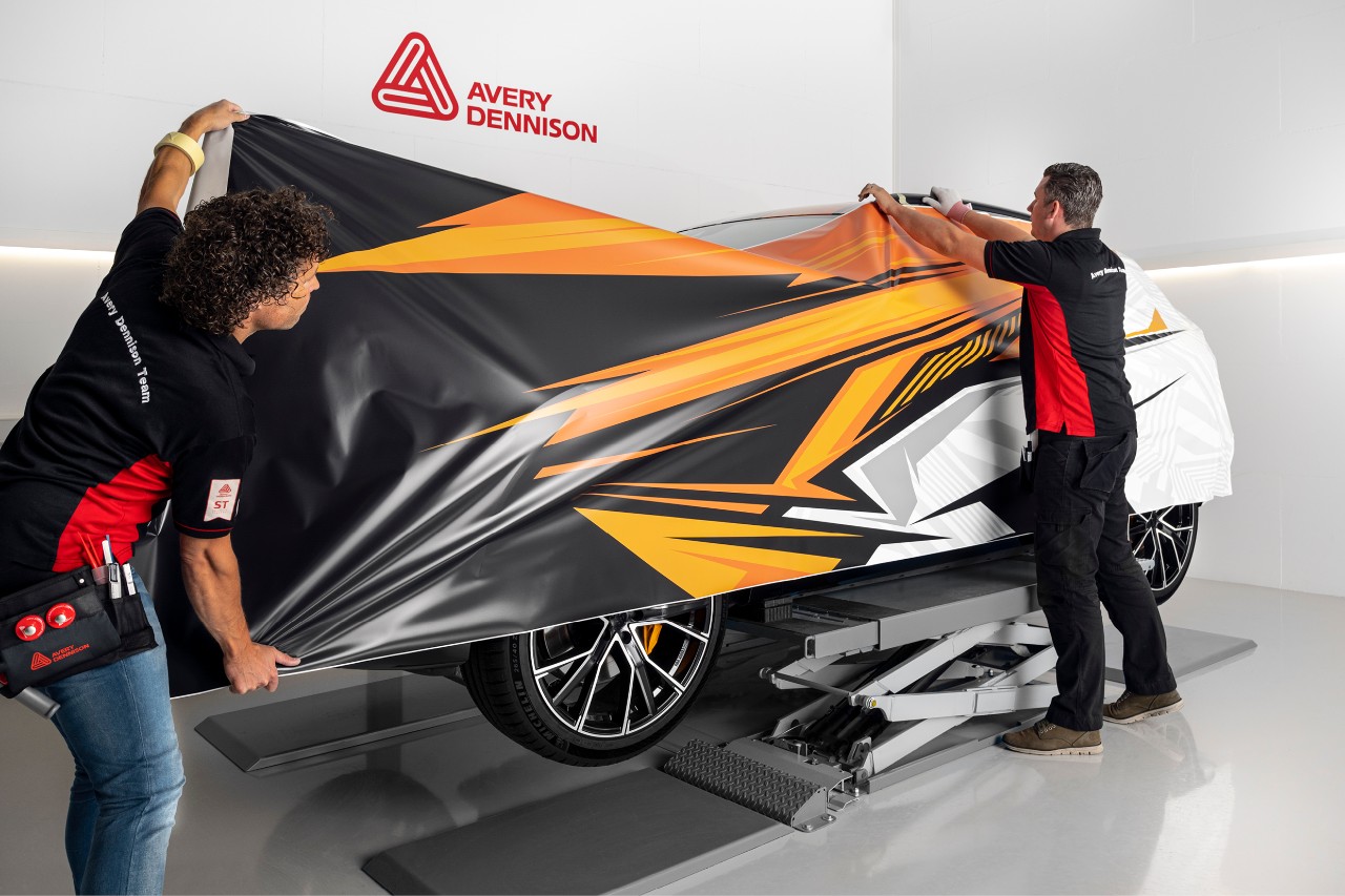 Avery Dennison installers positioning printed wrap film on a vehicle